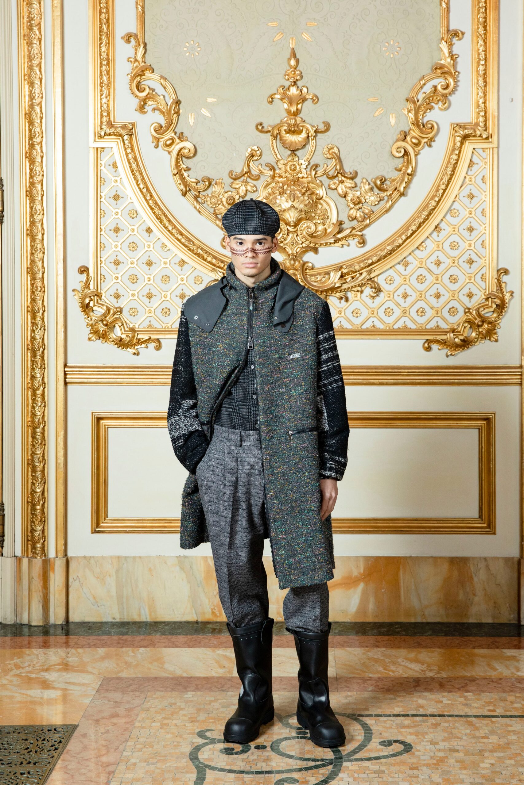 A relaxed black wool coat with long sleeves and a collared design, paired with gray pants.