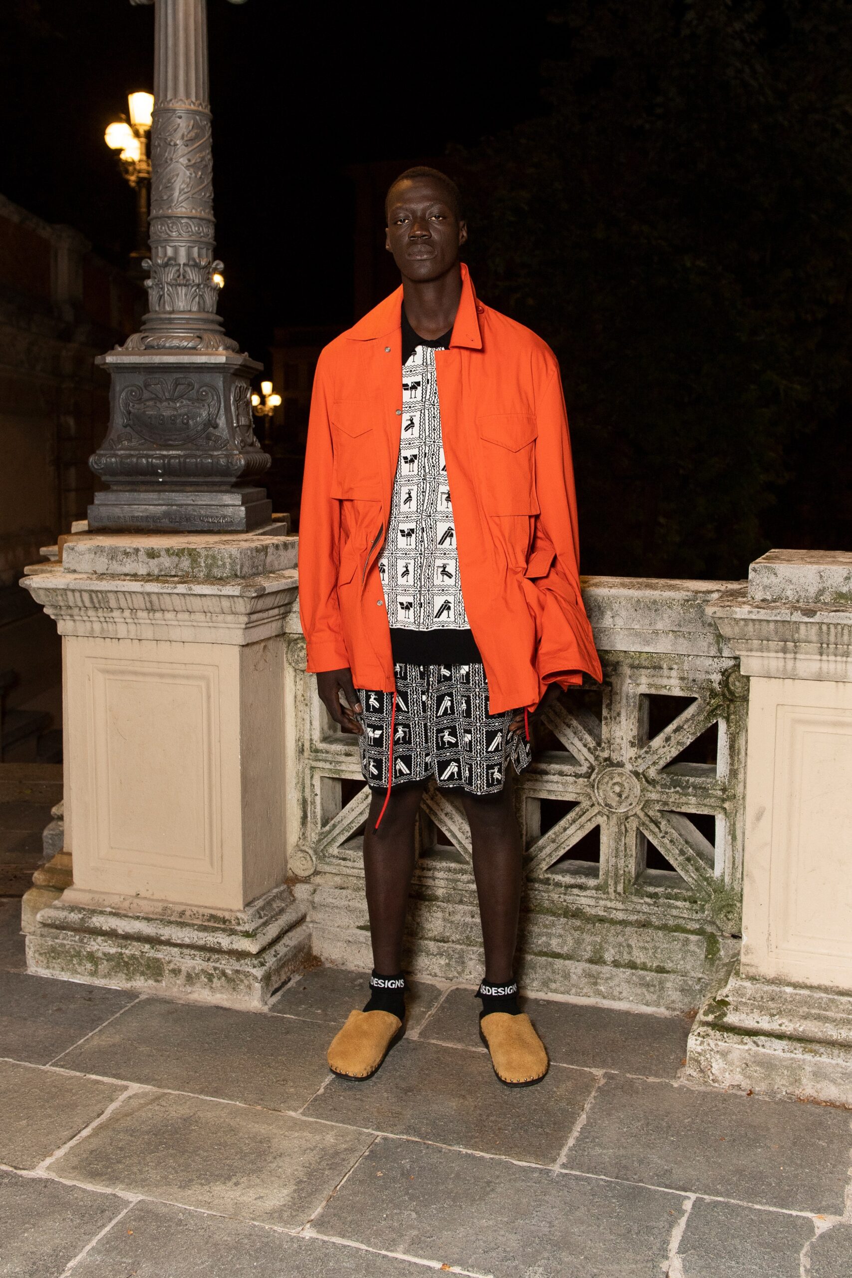 A relaxed-fit orange cotton jacket paired with black printed shorts.