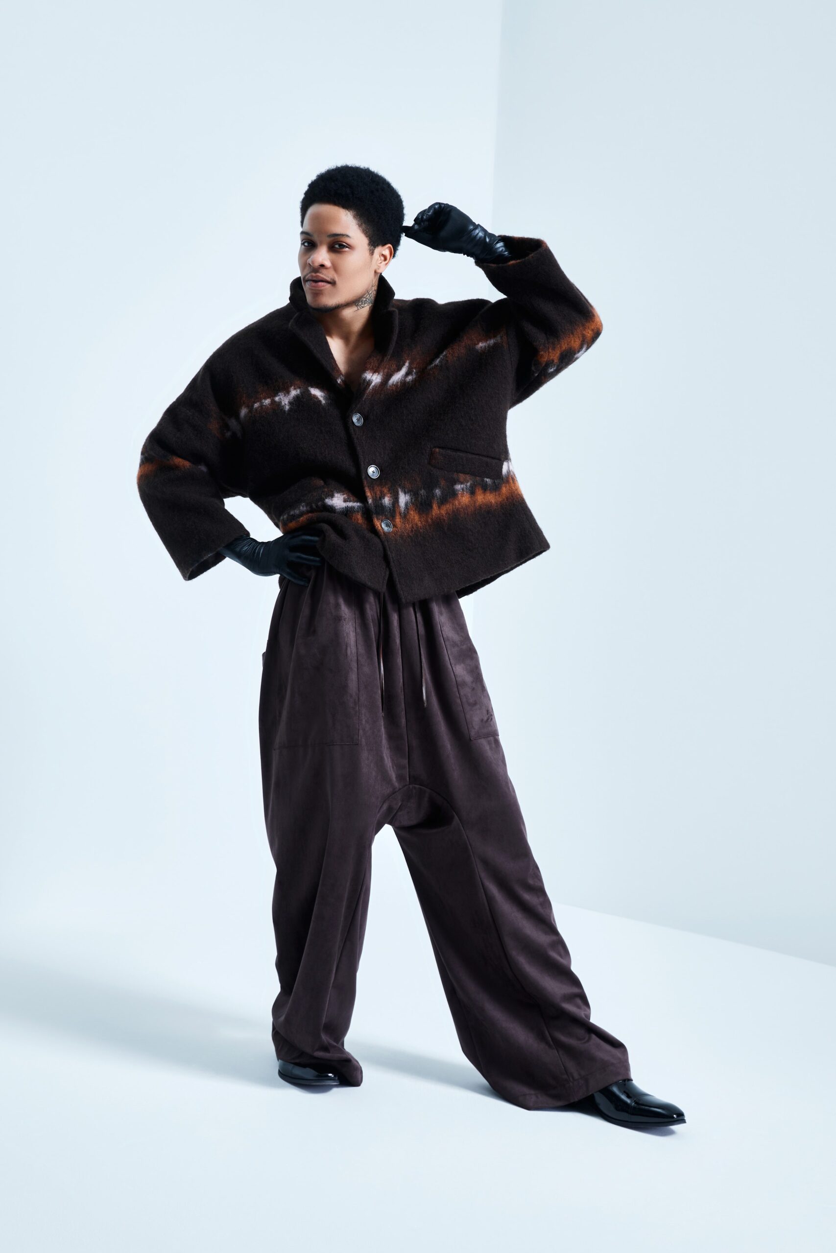 This relaxed jacket features a unique asymmetric design with a striking color pattern, complemented by a classic collared neckline. Paired with leather pants, the ensemble creates a bold silhouette that exudes modernity and sophistication.