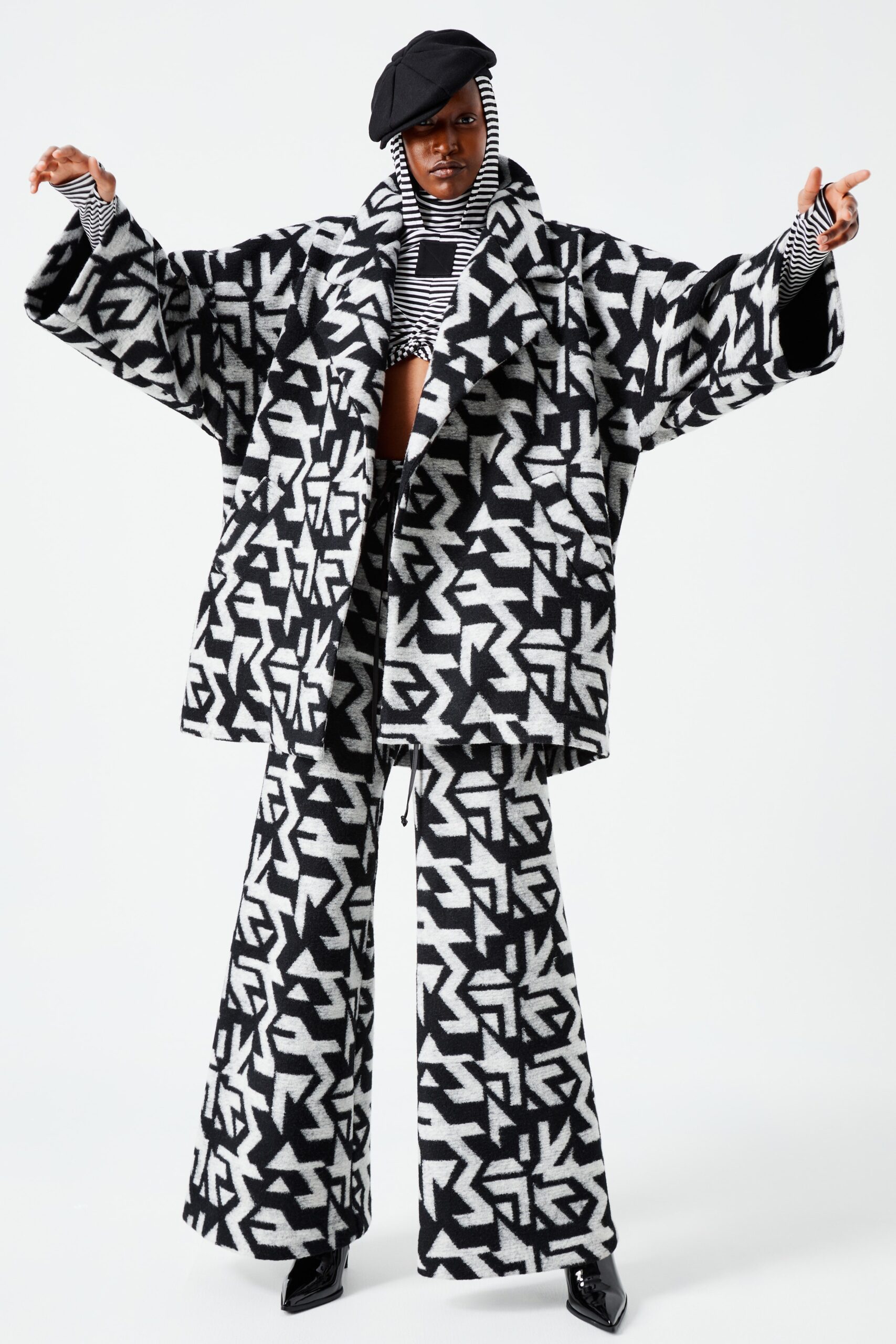 An oversized coat paired with wide-leg pants creates a striking silhouette in bold black and white prints. The long sleeves and collared design add structure, while the graphic pattern enhances visual interest, making a statement in any setting.