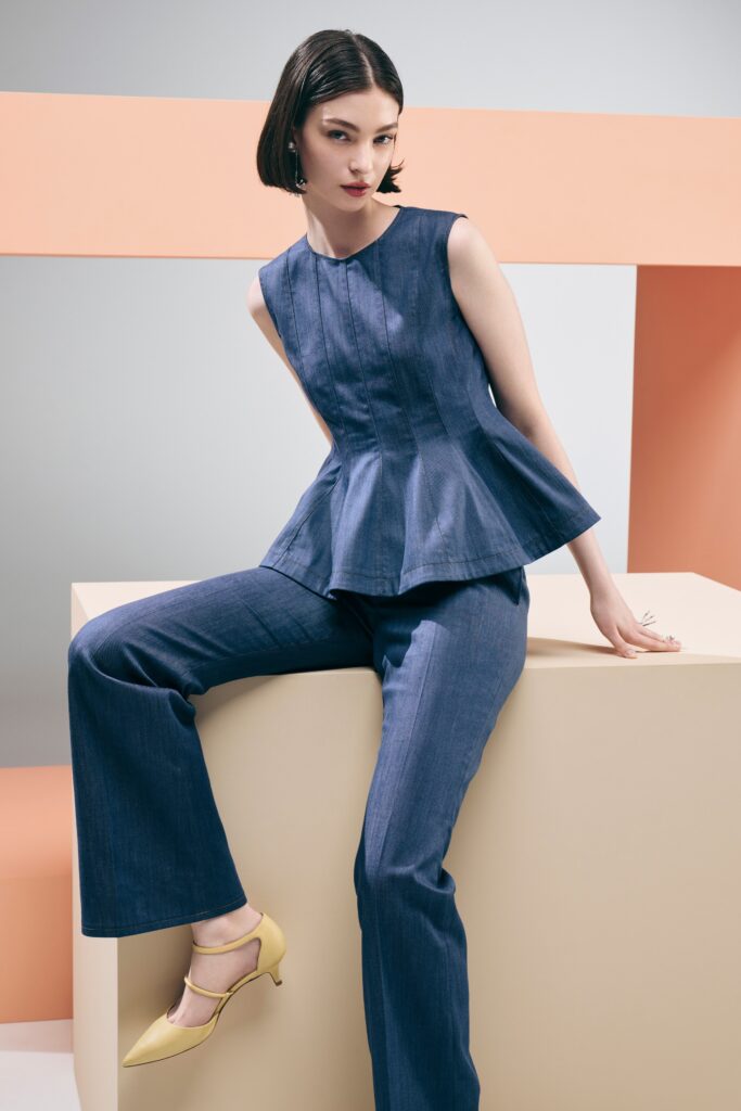 A fitted blue denim sleeveless top paired with flared denim pants.