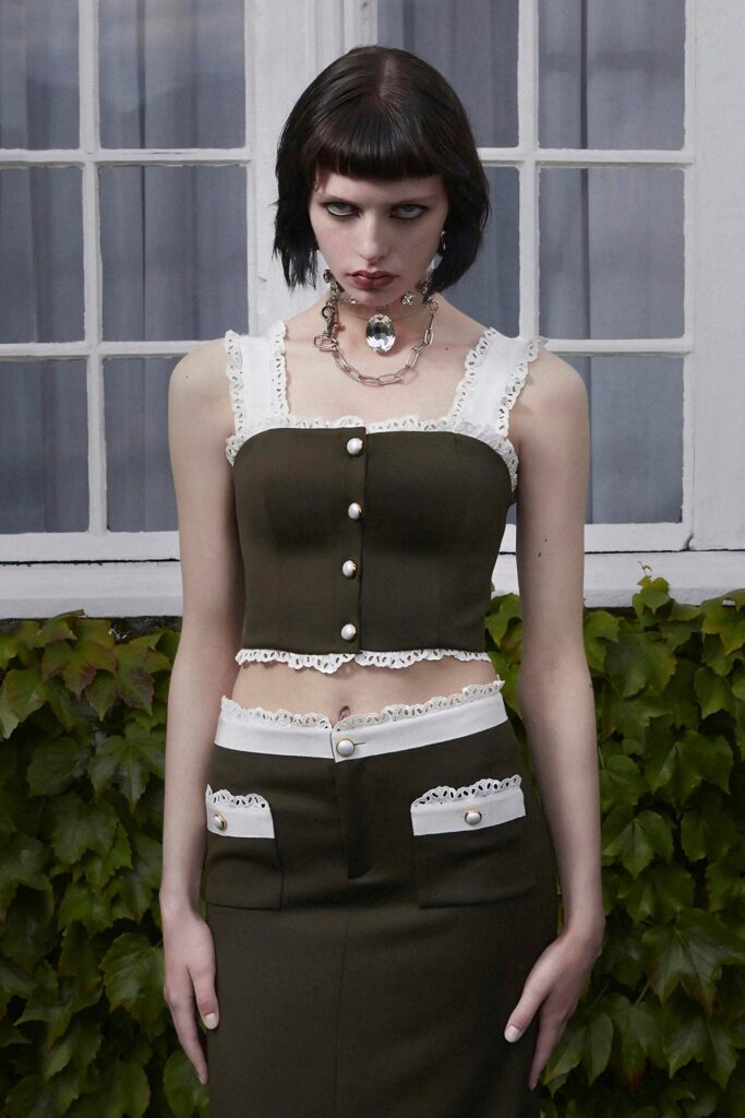 A fitted green cotton sleeveless top with a collared design and layered buttoned skirt.