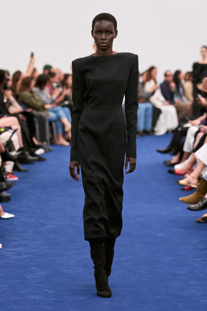 A fitted black dress with long sleeves and a high neckline, featuring a straight-leg silhouette.