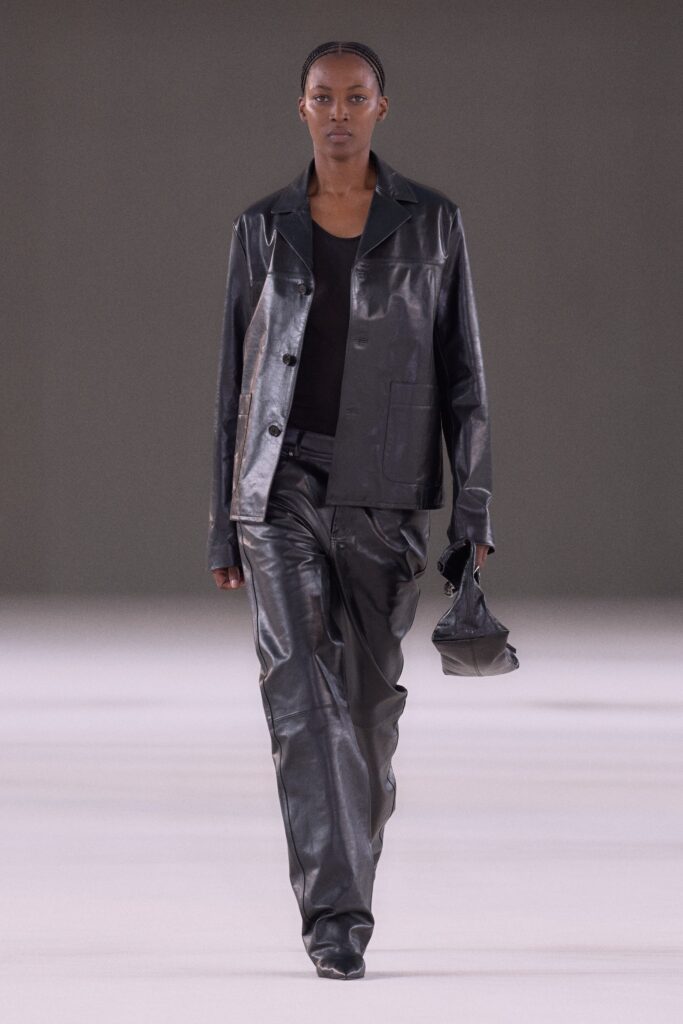 A fitted black leather jacket with long sleeves and collared design paired with straight-leg pants.
