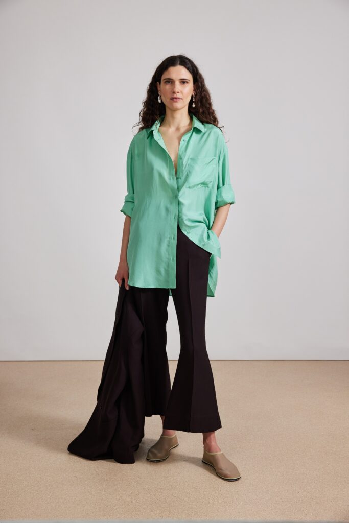A relaxed green silk long-sleeve shirt paired with black flared pants.