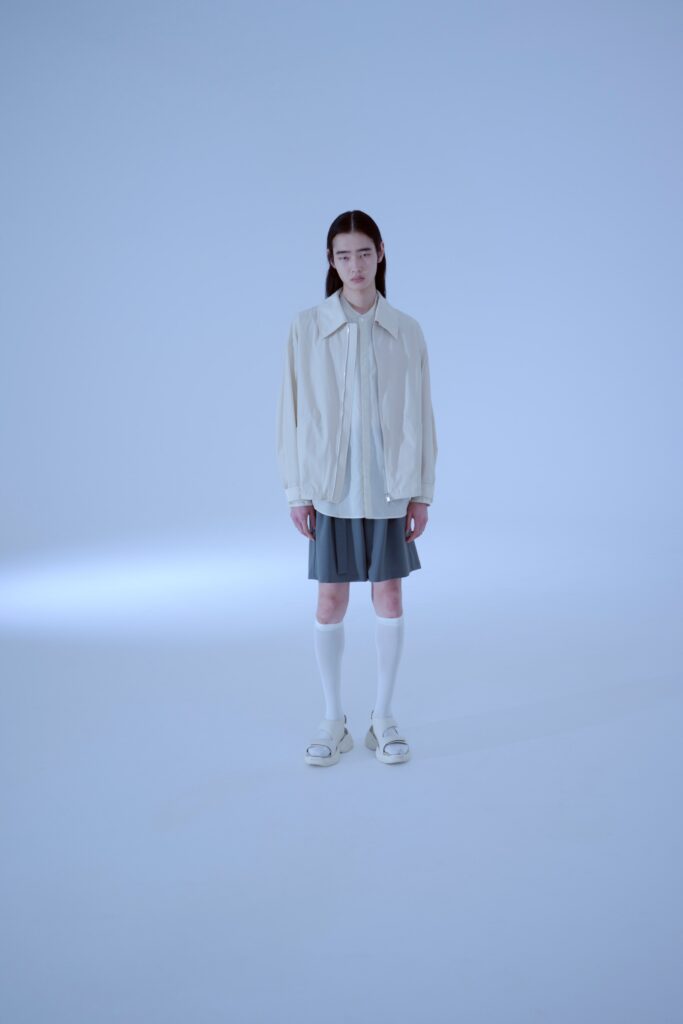A relaxed white jacket paired with a pleated gray skirt, featuring a collared neckline.
