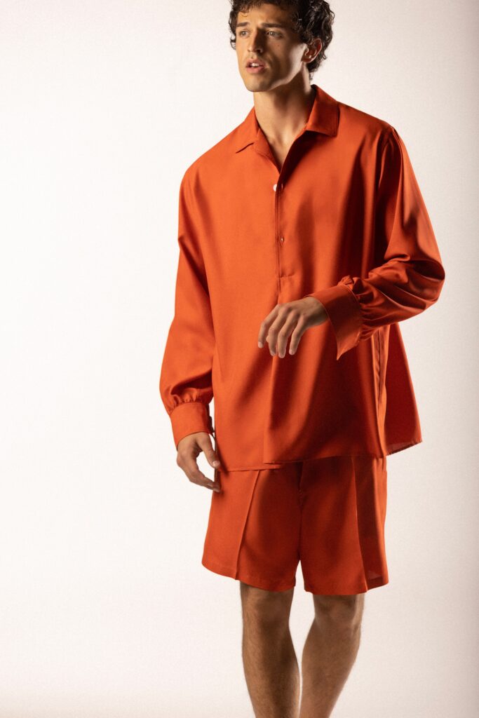 A relaxed orange silk shirt with long sleeves paired with matching shorts.