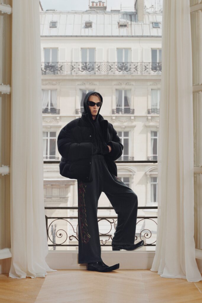A relaxed black cotton hooded jacket paired with matching pants featuring a zippered detail.