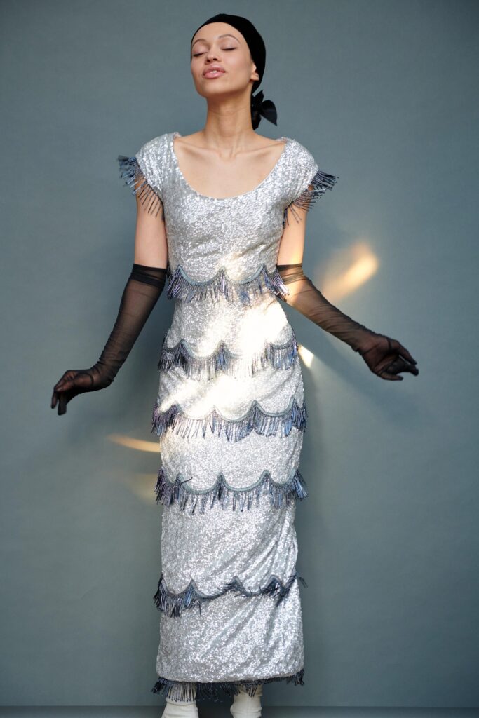 A fitted silver sequin dress with a round neckline and tiered fringed detailing.