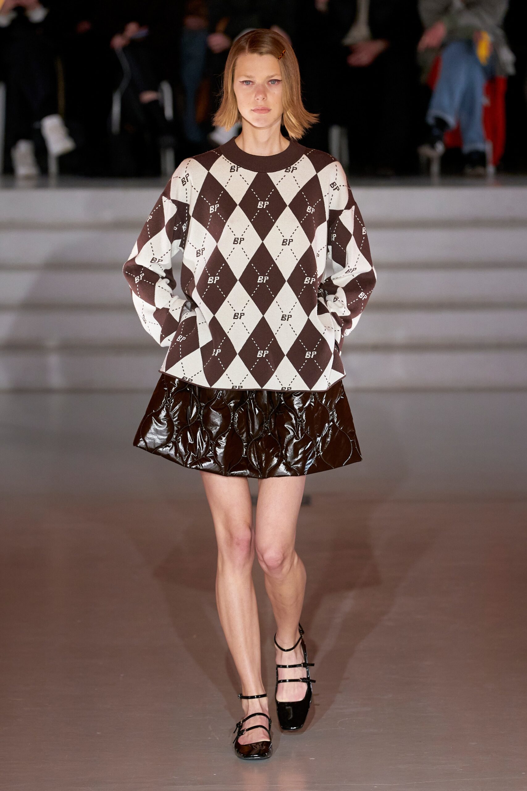 A fitted long-sleeve brown and white printed top paired with a pleated leather skirt.