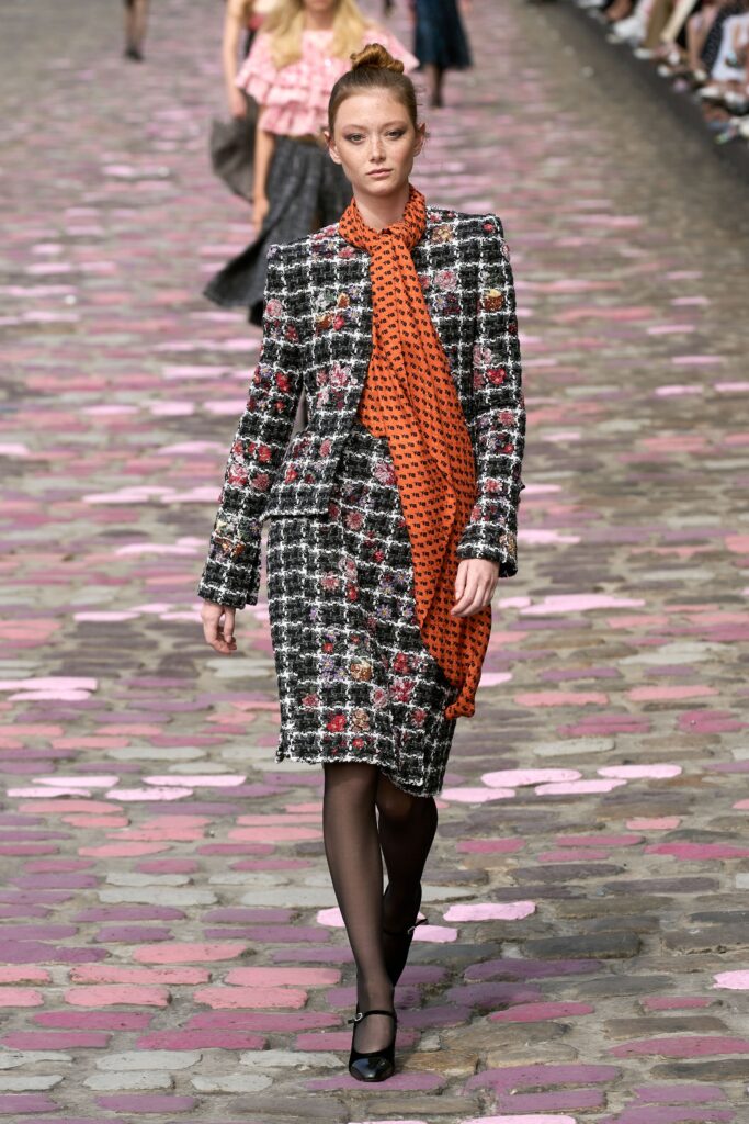 A fitted dress paired with a long-sleeve collared jacket featuring a printed design.