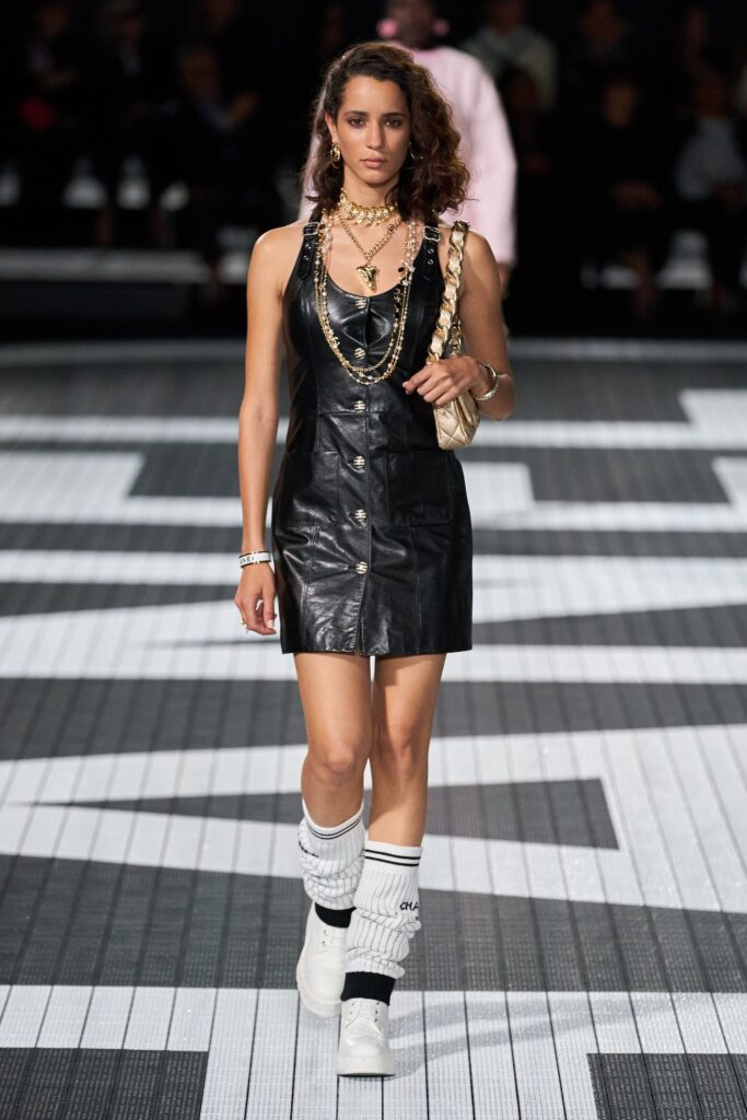 A fitted black leather mini dress with a sleeveless design and V-neckline.