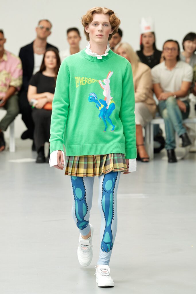 A relaxed fit green cotton sweater with embroidery paired with a pleated plaid skirt.