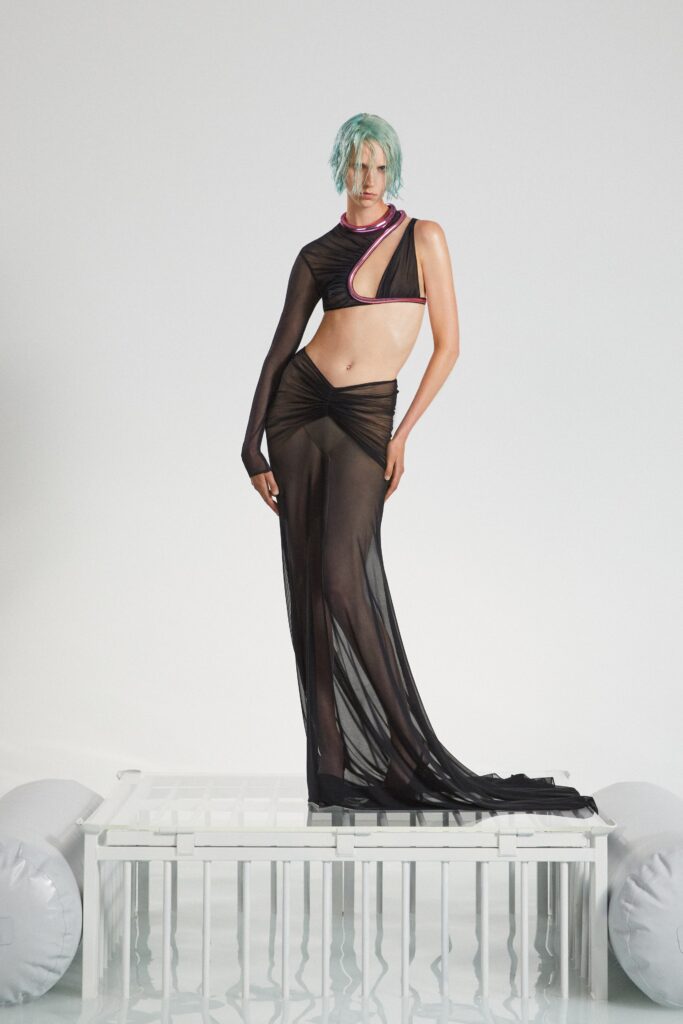 A fitted black sheer dress with an asymmetric design and draped detailing.