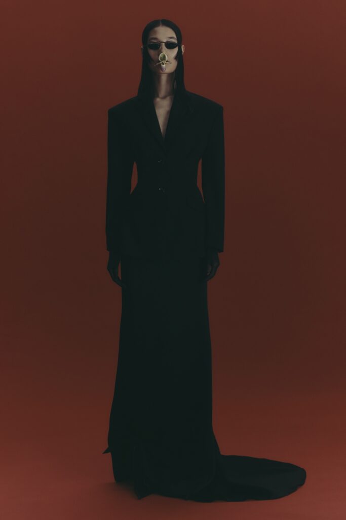 A fitted black silk gown with long sleeves and an asymmetric design.