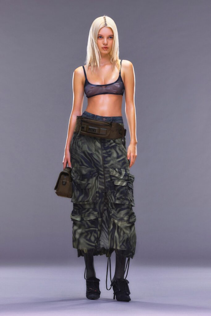 A fitted black sleeveless top paired with a high-waisted asymmetric layered green skirt.