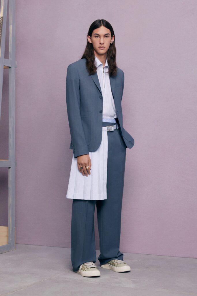 A tailored blue suit paired with a white long-sleeve shirt and unique skirt detail.