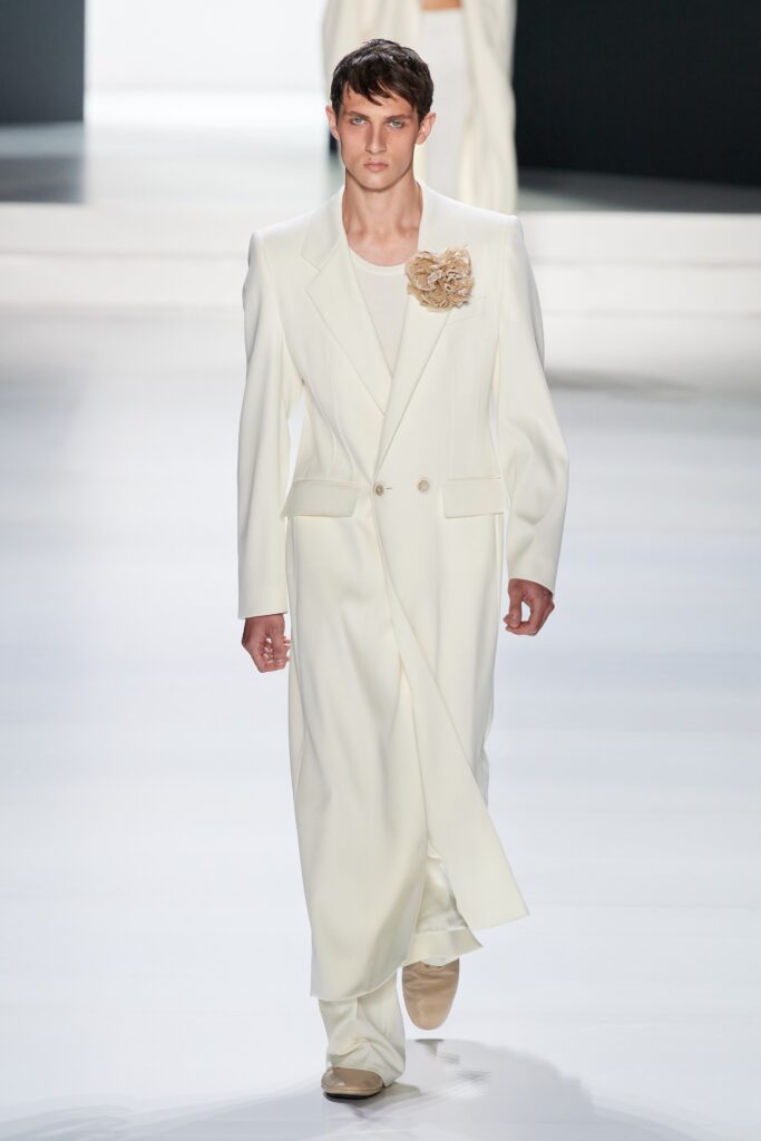 A tailored white suit with long sleeves and an asymmetric design detail.
