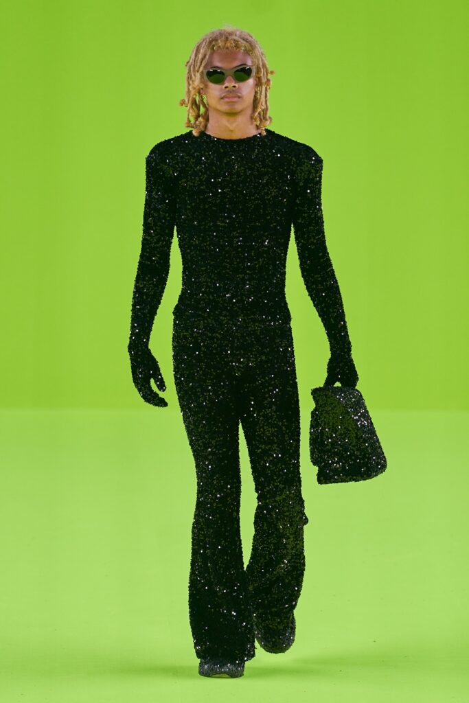 A fitted black sequined jumpsuit with long sleeves and a high neck, featuring a flared silhouette.