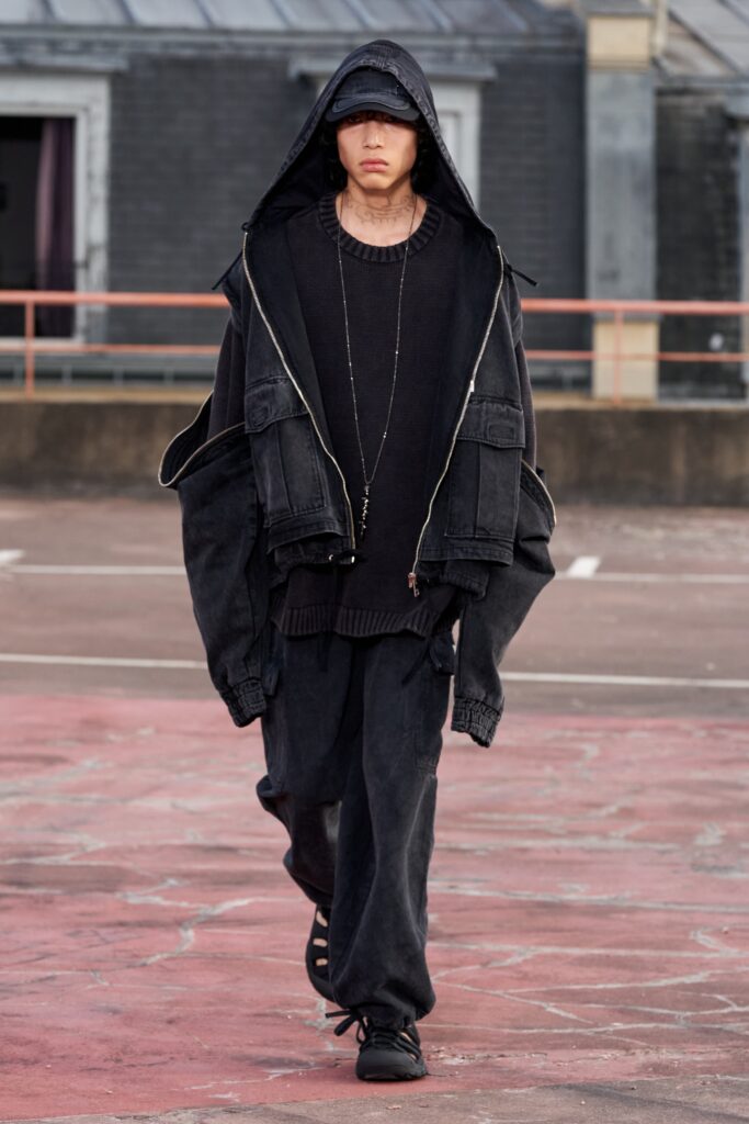 An oversized black denim jacket with a hood paired with matching pants, creating a layered look.