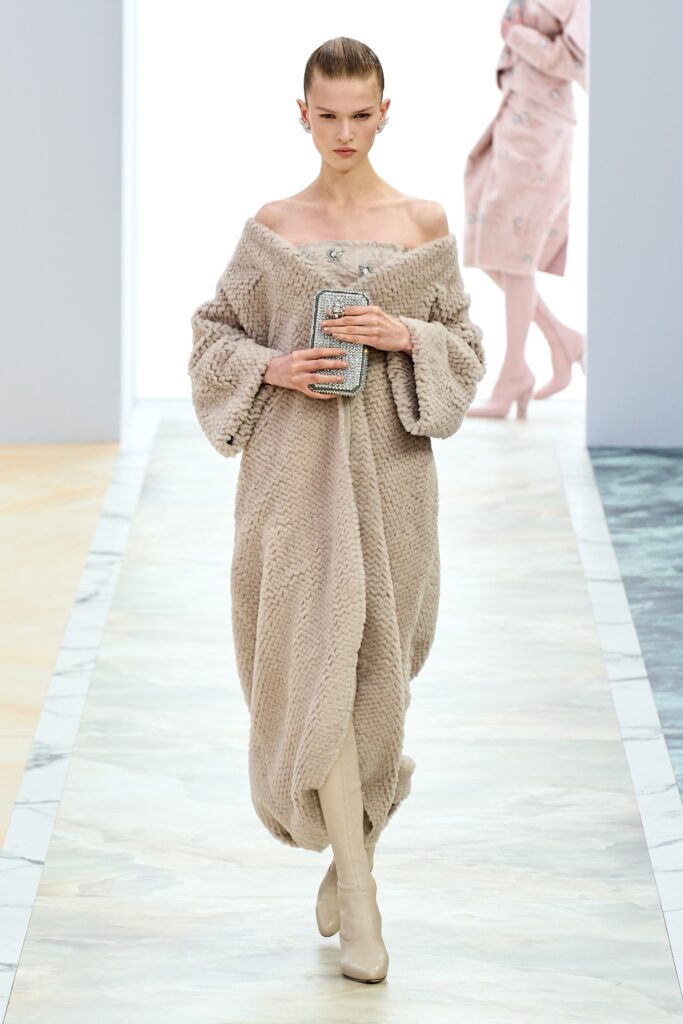 A relaxed beige fur off-shoulder dress with a draped silhouette.