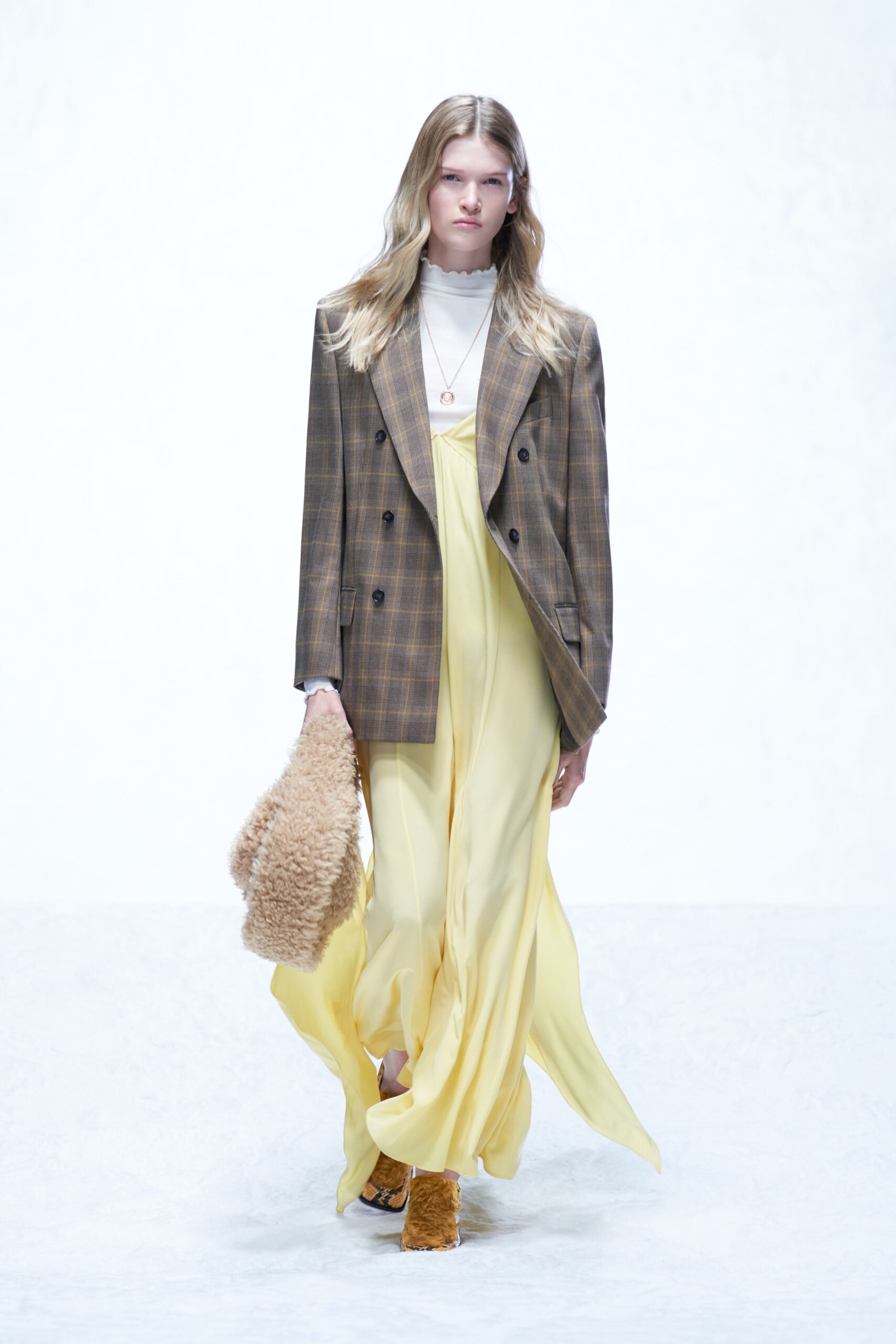 A relaxed yellow silk dress layered under a brown plaid blazer with a collared neckline.