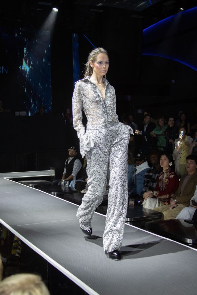A fitted silver sequined jumpsuit with long sleeves and a collared neckline.