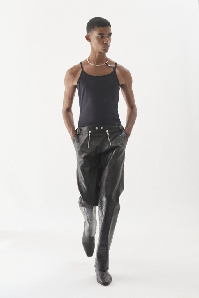 A fitted black leather sleeveless tank-top paired with high-waisted straight-leg pants.