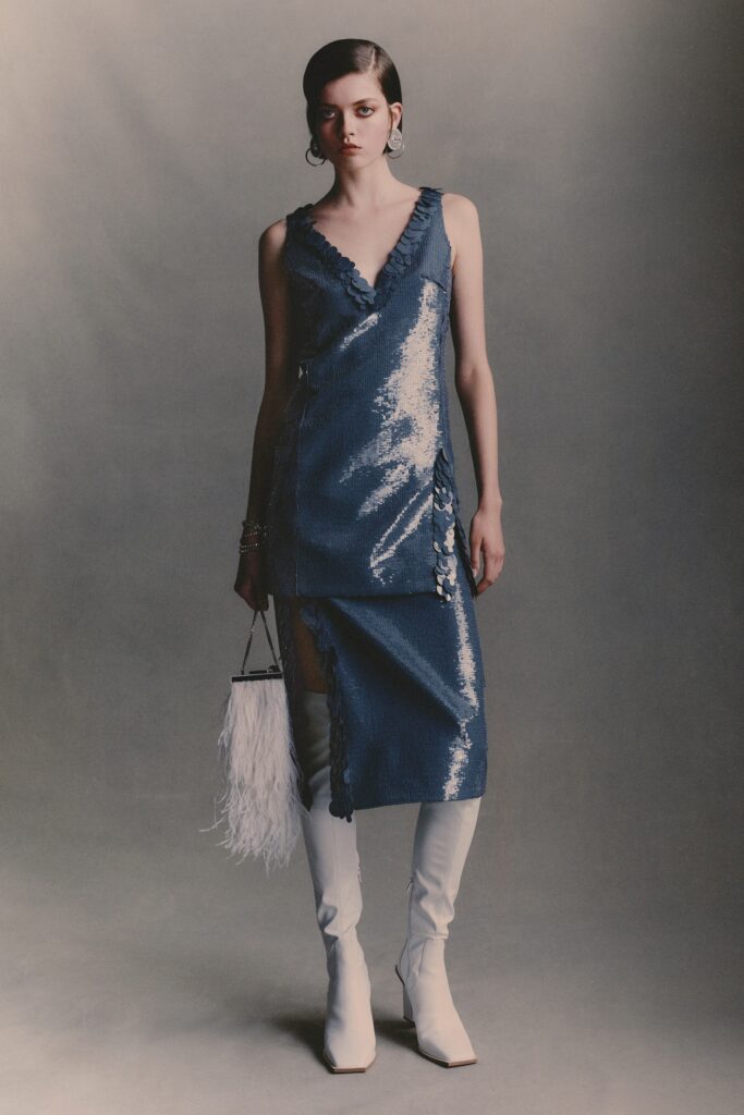 A fitted blue silk sleeveless dress with a V-neckline and asymmetric design.