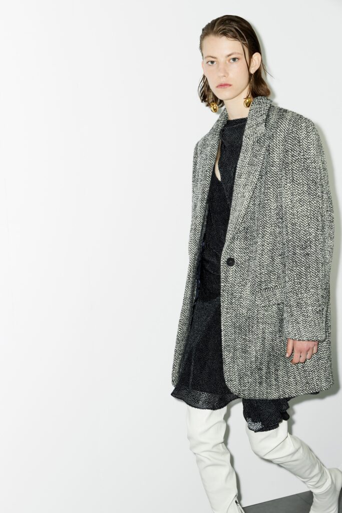 A fitted black dress layered under a gray wool coat with an asymmetric design.