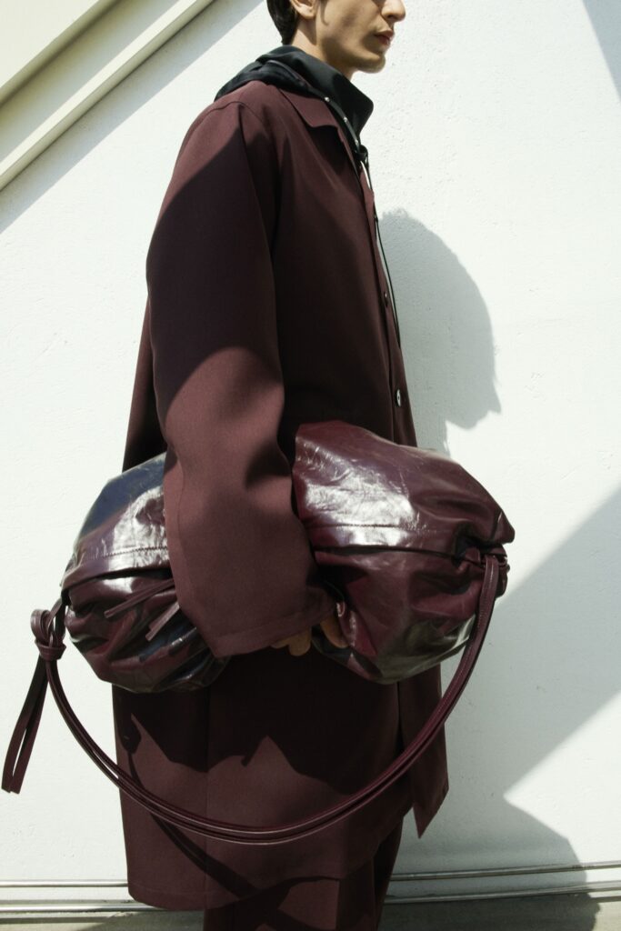 An oversized burgundy wool coat with long sleeves and a layered design.
