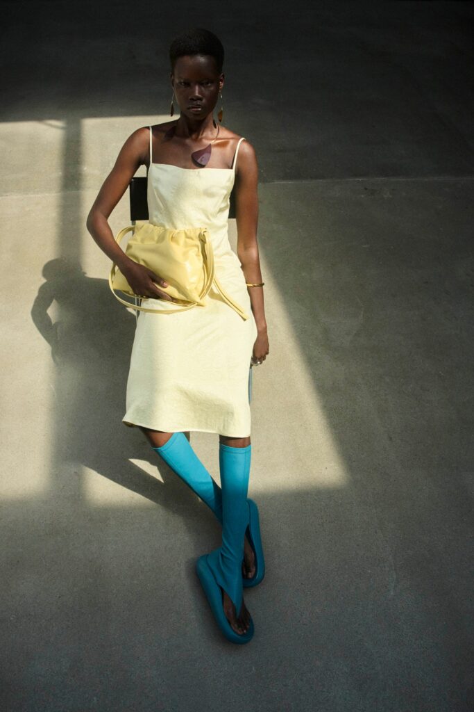 A fitted yellow cotton dress with a sleeveless design and V-neckline.