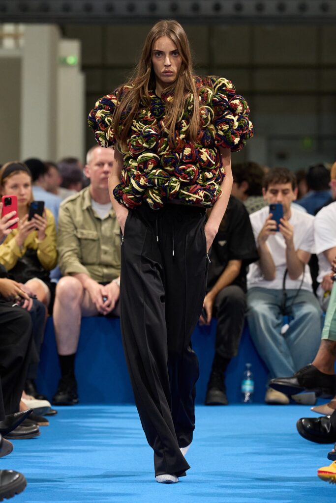A relaxed multicolor top with long sleeves paired with black pants, featuring a layered design.