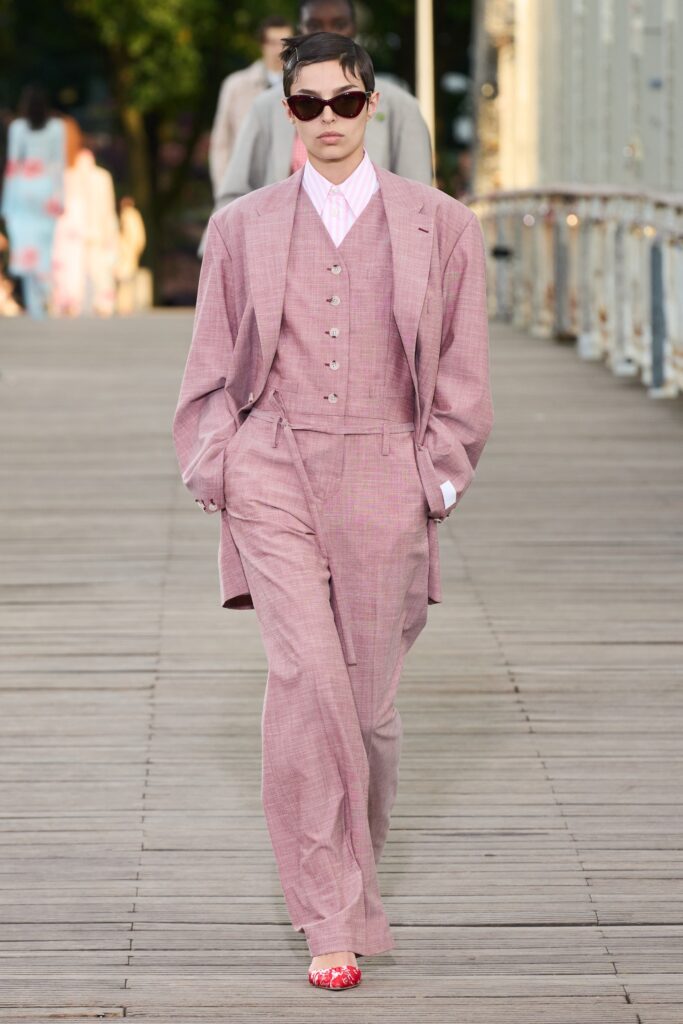 A tailored pink suit with long sleeves, a collared shirt, and wide-leg trousers.