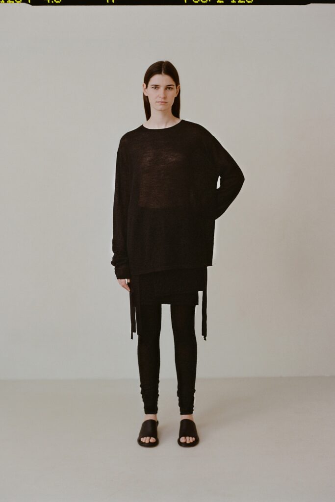 An oversized black cotton top with long sleeves paired with black leggings, featuring a layered design.