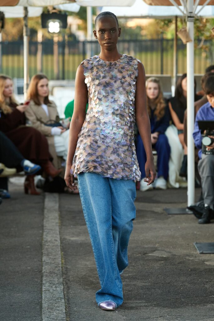 A relaxed-fit multicolor sleeveless top paired with blue denim pants.