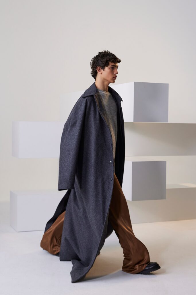 A relaxed gray wool coat with a collared design paired with wide-leg brown silk pants.