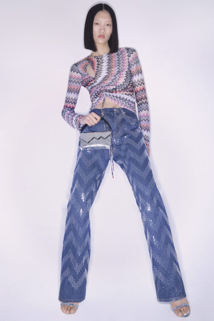 A fitted long-sleeve striped top with cutout details paired with wide-leg denim pants.