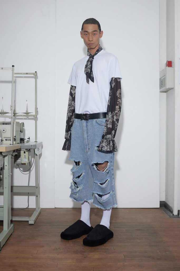 A relaxed white long-sleeve shirt paired with distressed blue denim pants.