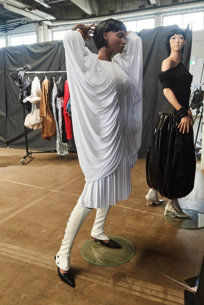 A relaxed white silk dress with long sleeves and a V-neckline featuring draped detailing.