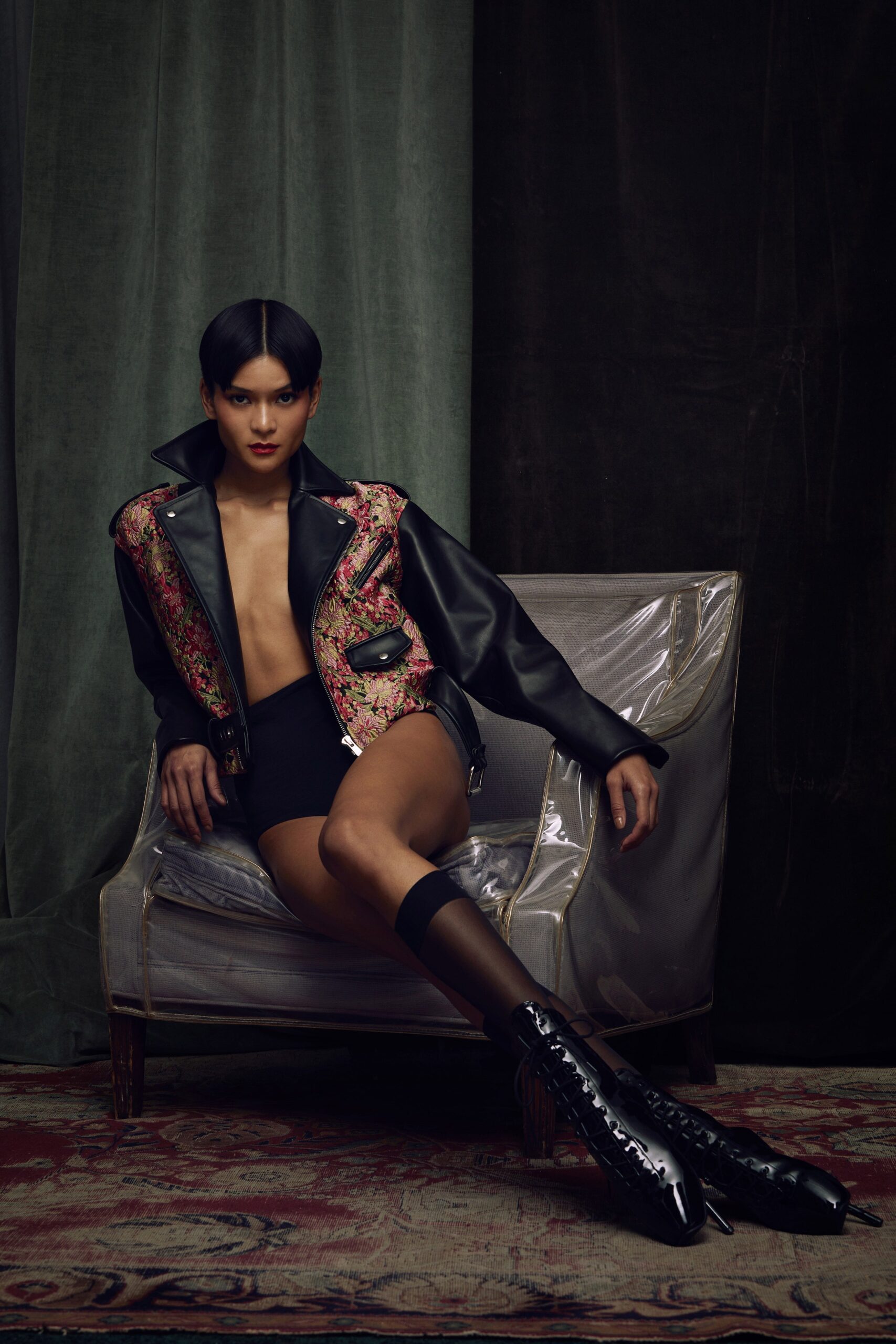 A fitted black leather jacket with multicolor embroidery and a sleeveless design.