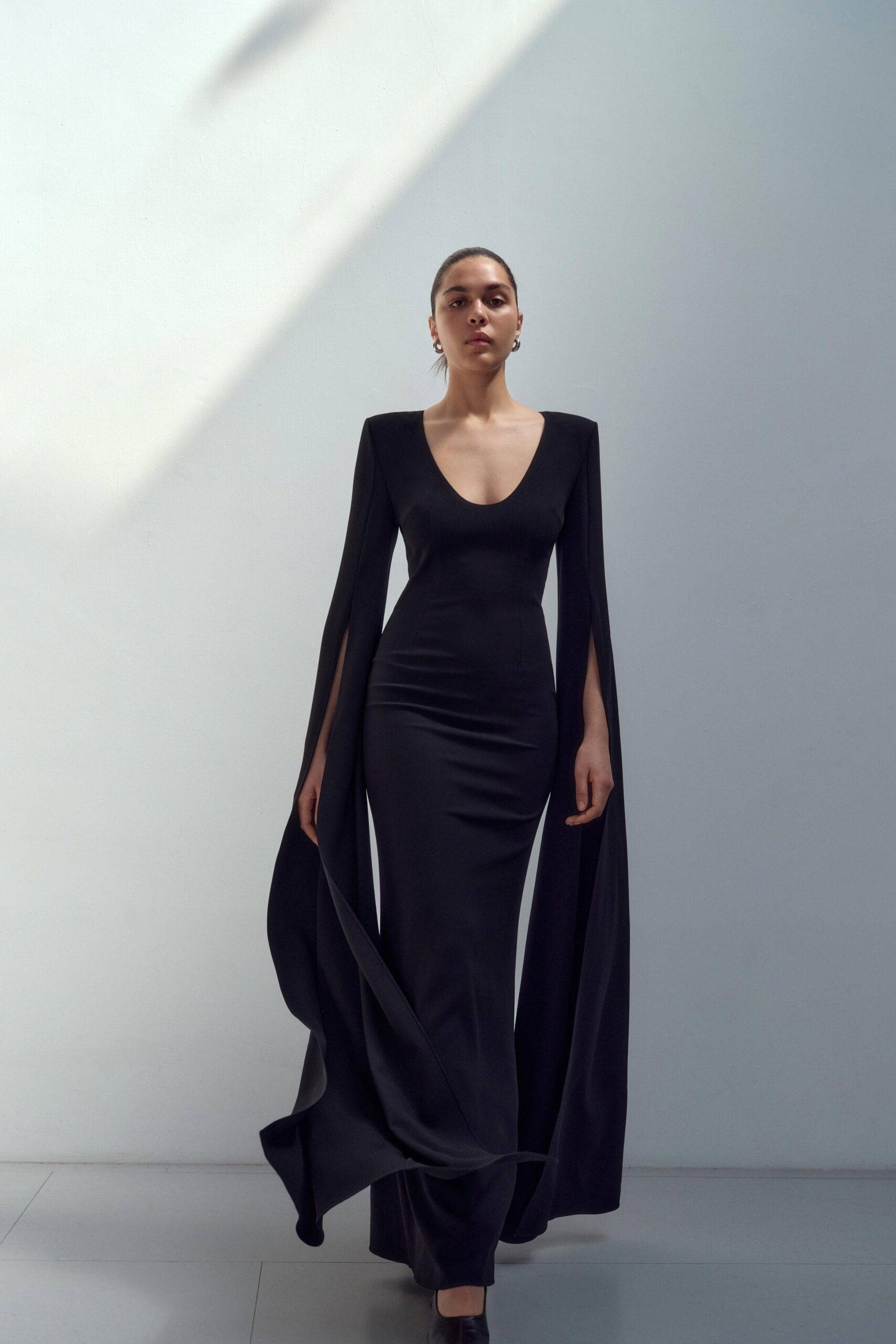 A fitted black silk dress with a V-neckline and asymmetric design details.