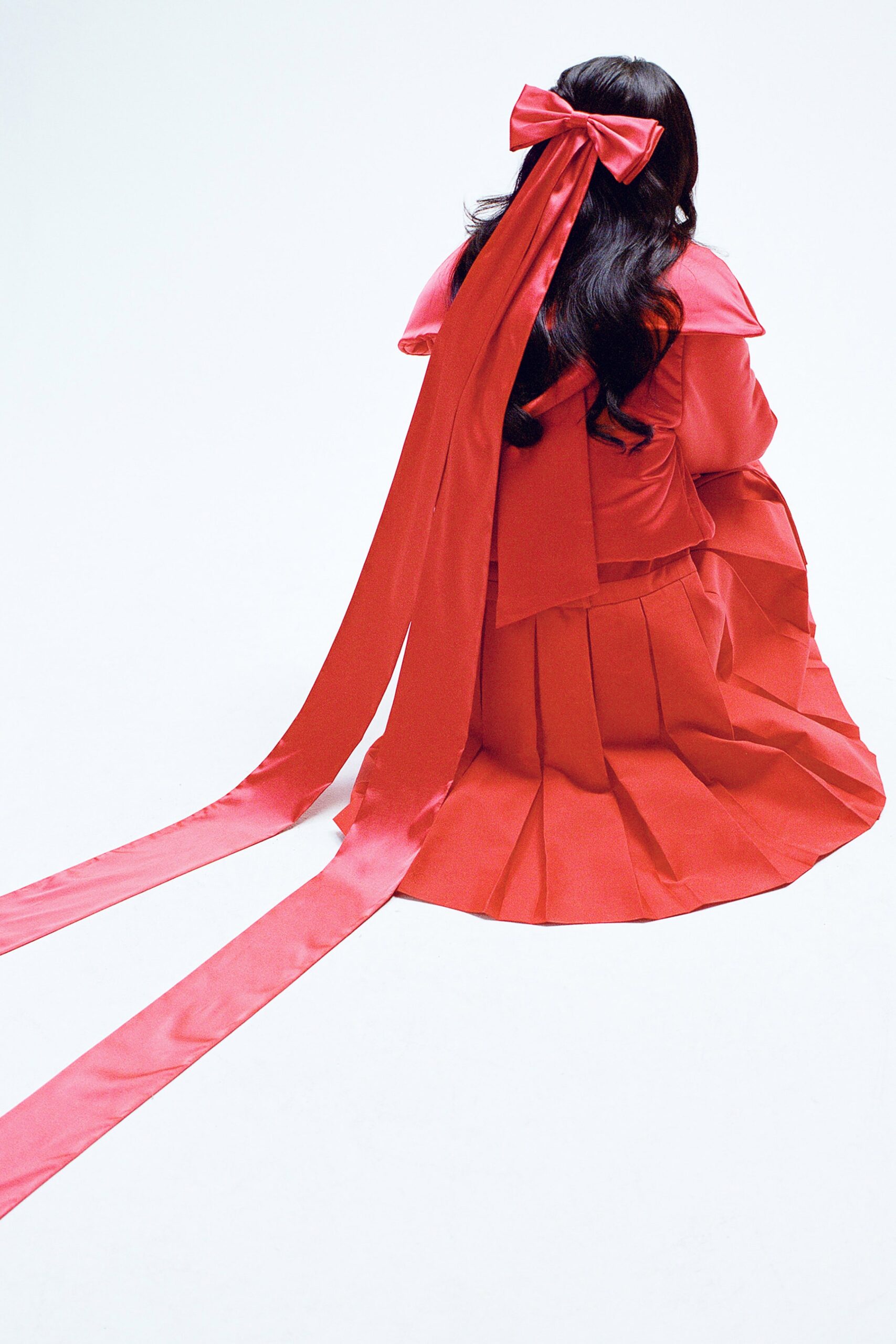 A relaxed red silk sleeveless dress with a high neckline and pleated design.
