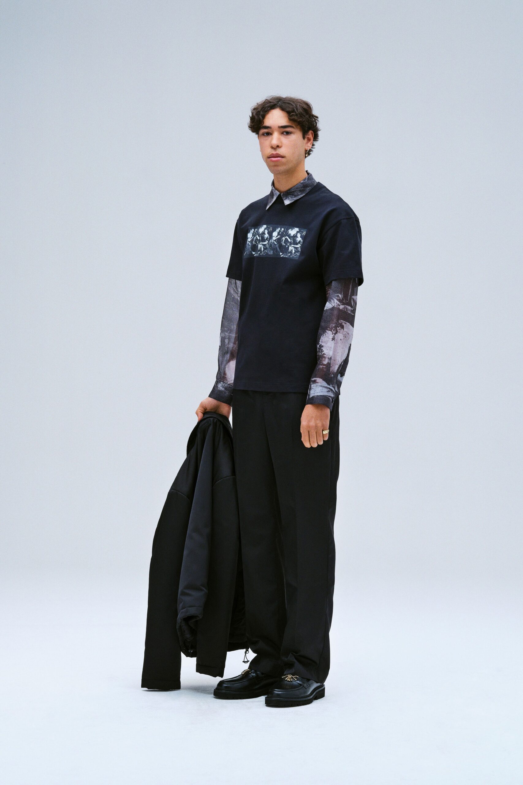 A relaxed black shirt with a printed design paired with black pants.