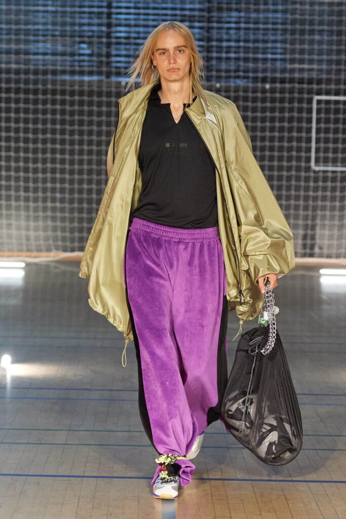 A relaxed green silk jacket paired with purple pants, featuring a layered design.