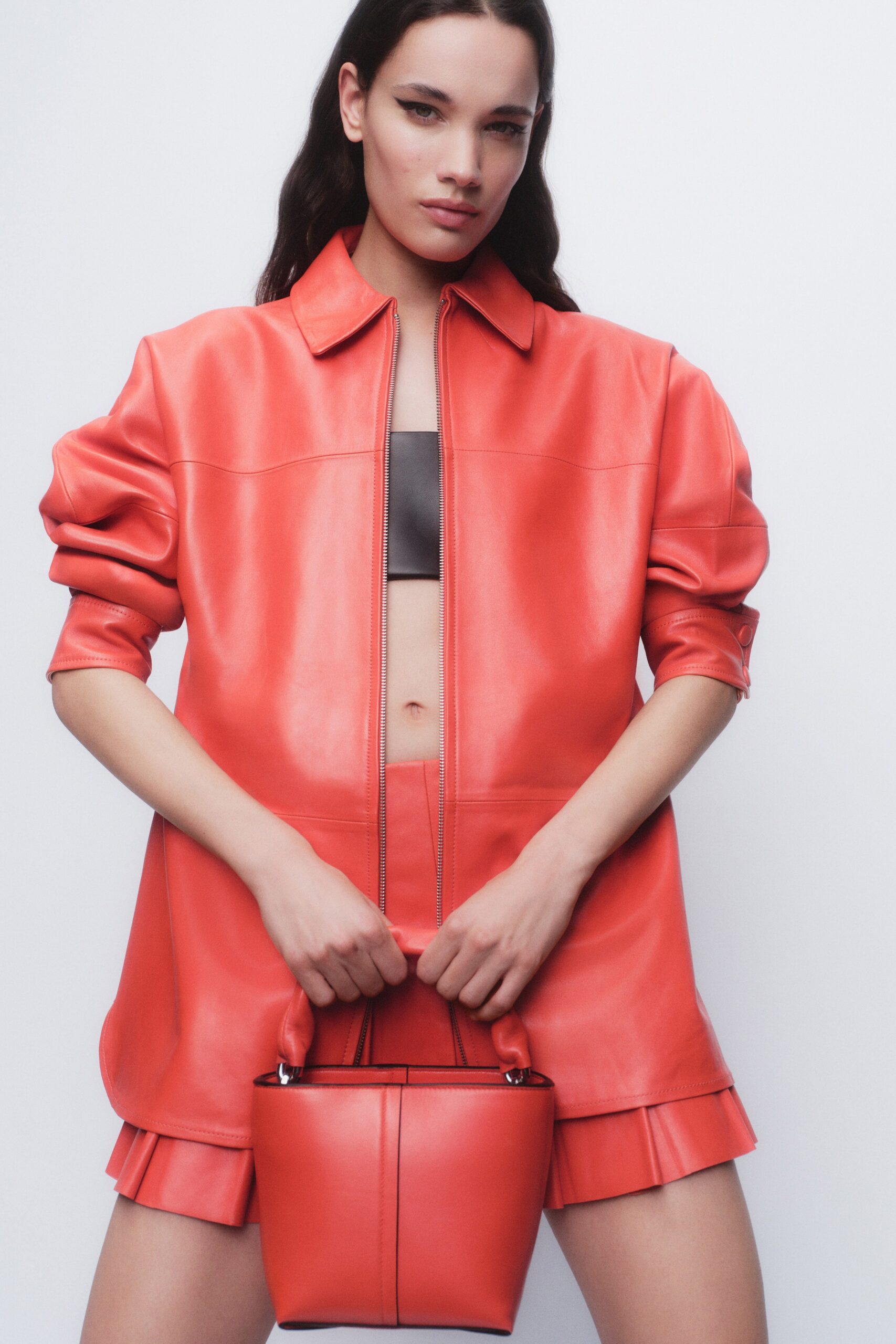 A fitted red leather jacket with short sleeves and a pleated skirt.