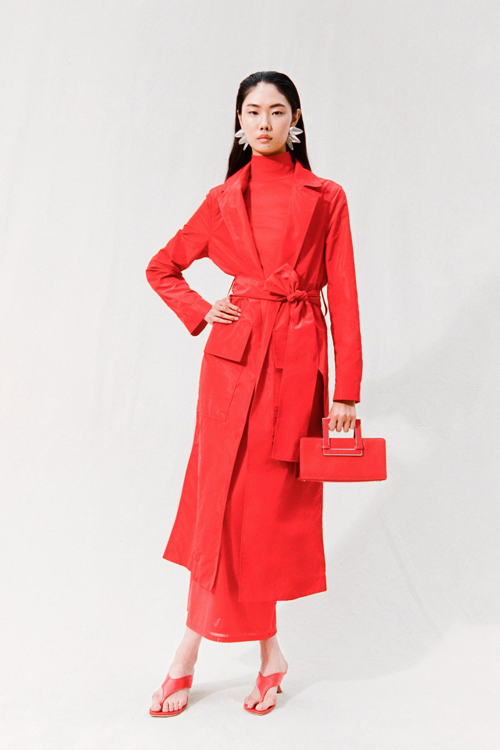 A fitted red coat dress with long sleeves, a collared neckline, and belted detail.