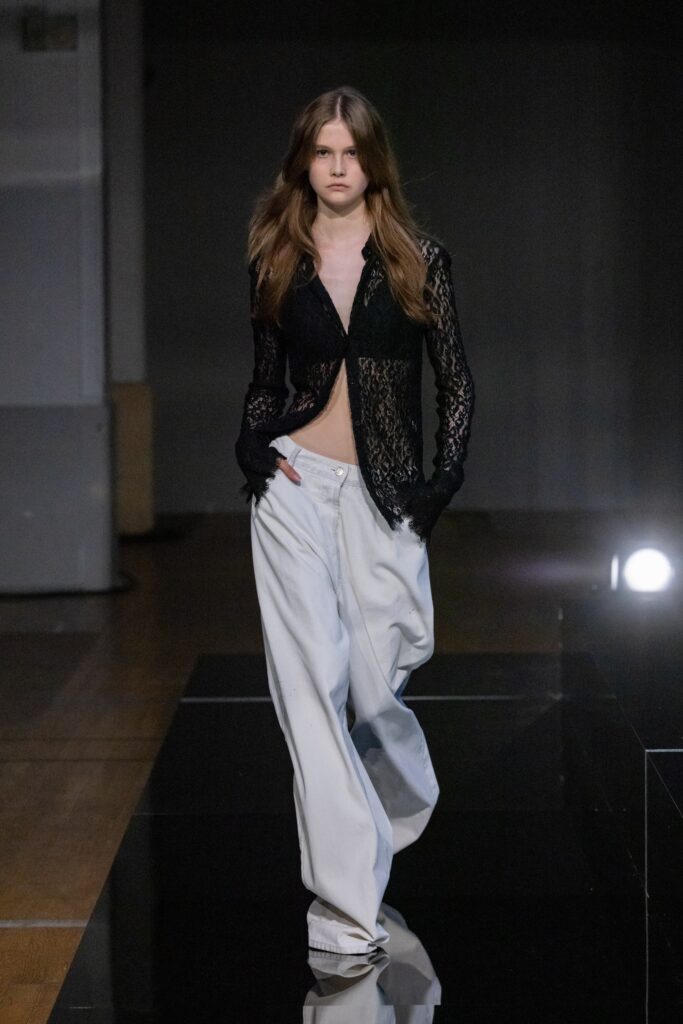 A relaxed black lace long-sleeve top paired with wide-leg white pants.