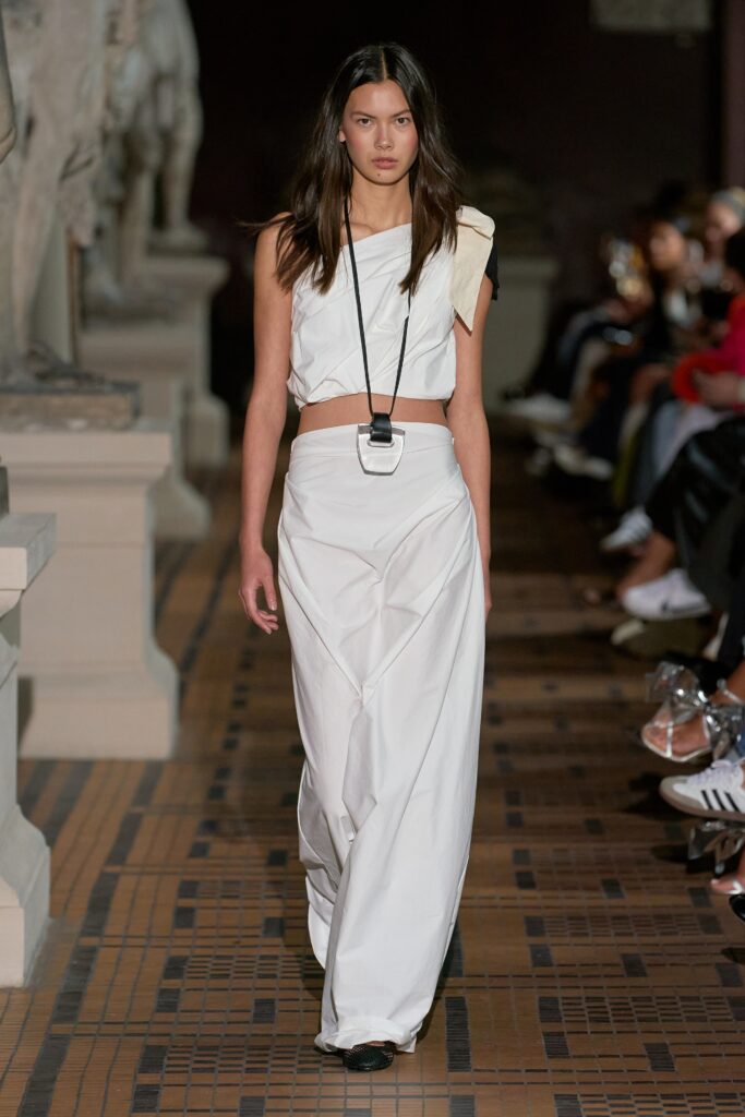 A relaxed white sleeveless top with a high neckline and an asymmetric skirt.