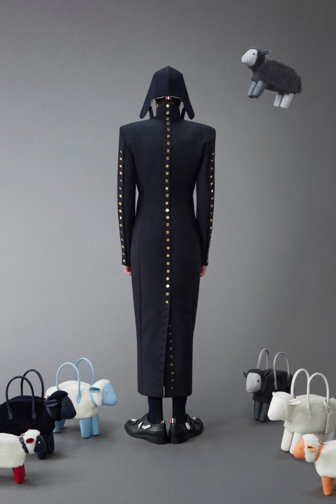 A fitted black cotton coat with long sleeves and an asymmetric design featuring a hood.